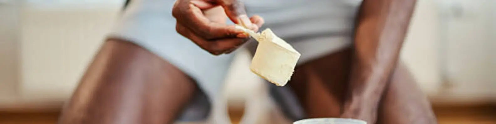 Man scooping creatine at the gym into a bottle image