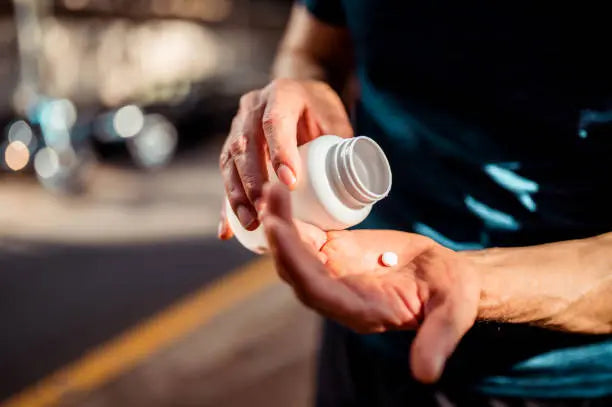 Man dumping supplements in his hand for the gym and workout session