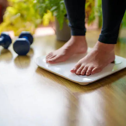 Women stepping on the scale after working out to see if she is in a weight loss plateau