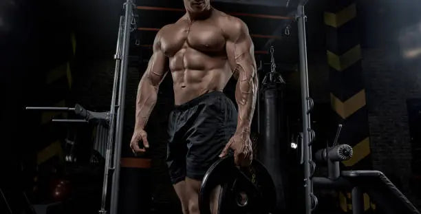 Man who is very bulk in the gym working out his msucles ot build them and get bigger and have mass gains 