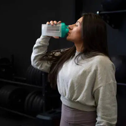 A women in the gym drinking her creatine with water 
