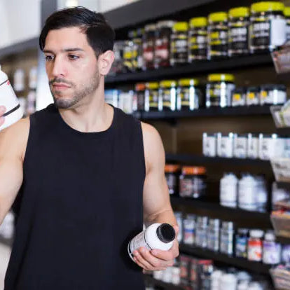 Man in store looking at different creatine bottles determining which one he wants to buy