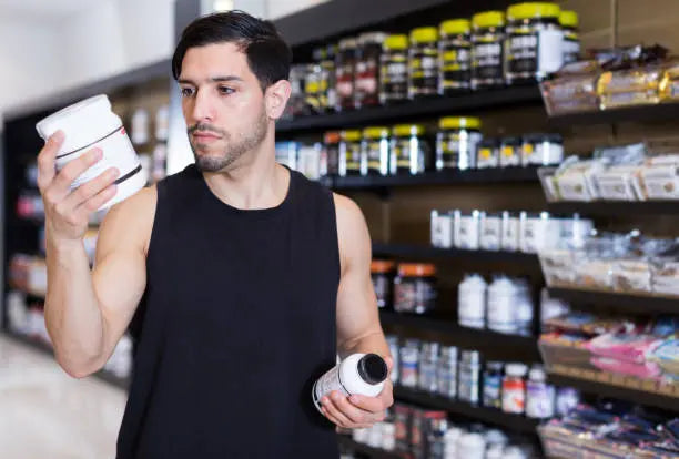 Man in store looking at different creatine bottles determining which one he wants to buy