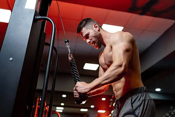 Buff man in a red gym doing an arm workout 