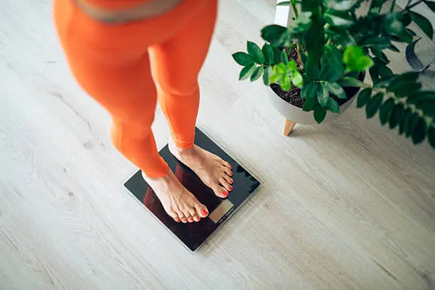 Women in orange leggings standing on scale 