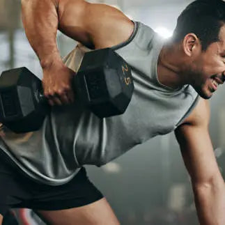 Man working out intensily with a heavy dumbell at the gym