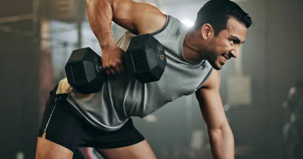Man working out intensily with a heavy dumbell at the gym